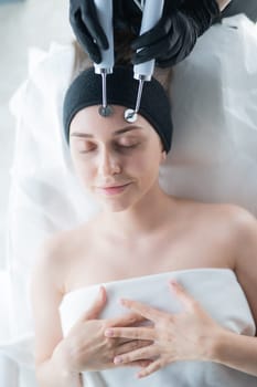 Young caucasian woman on microcurrent therapy procedure. Beautician's office