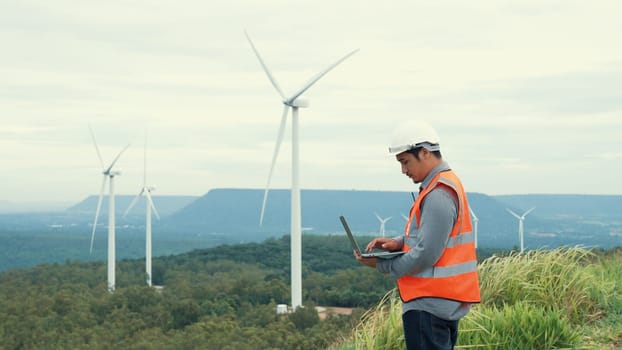 Engineer working on a wind farm atop a hill or mountain in the rural. Progressive ideal for the future production of renewable, sustainable energy. Energy generation from wind turbine.