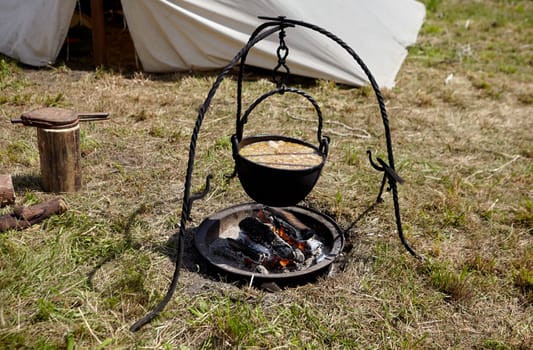 Camping. Soup in a pot over a fire. Stylization under the Middle Ages, vintage.