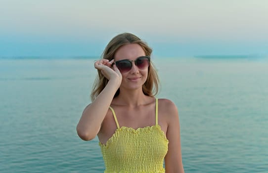 Portrait of a beautiful young woman in sunglasses early in the morning on the beach.
