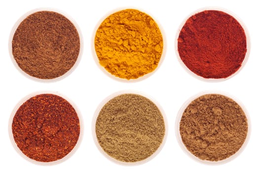 collection of indian spices (cumin, coriander, paprika, garam masala, curcuma, red pepper flakes) on glass cups isolated on white background