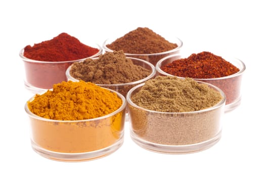 collection of indian spices (cumin, coriander, paprika, garam masala, curcuma, chili powder) on glass cups isolated on white background