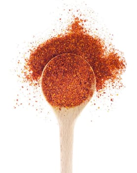 piri-piri flakes spice on a wooden spoon, isolated on white background