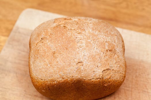 Whole wheat loaf from a bread making machine ready to cut on cutting board