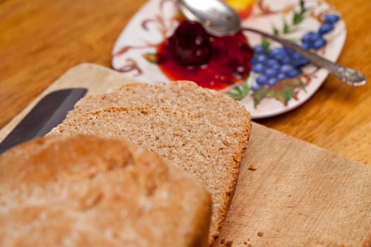 Slices of home made wheat bread on breadboard with knife