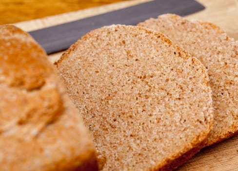 Slices of home made wheat bread on breadboard with knife