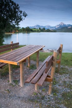 Table and bench made of wooden boards at a lake (Wessensee) in the Allgäu / Schwangau / Bavaria at dusk