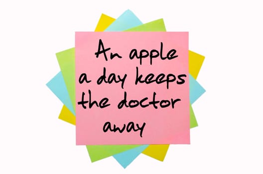 text "An apple a day keeps the doctor away"" written by hand font on bunch of colored sticky notes"