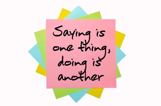 text " Saying is one thing, doing is another "" written by hand font on bunch of colored sticky notes"