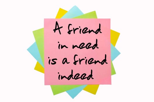 text "A friend in need is a friend indeed"" written by hand font on bunch of colored sticky notes"