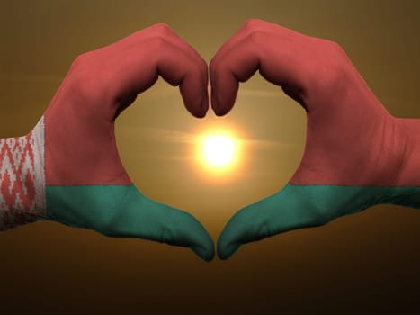 Gesture made by belarus flag colored hands showing symbol of heart and love during sunrise