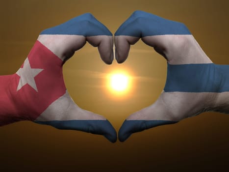 Gesture made by cuba flag colored hands showing symbol of heart and love during sunrise