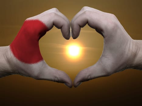 Gesture made by japan flag colored hands showing symbol of heart and love during sunrise