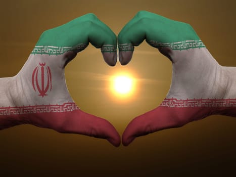 Gesture made by iran flag colored hands showing symbol of heart and love during sunrise