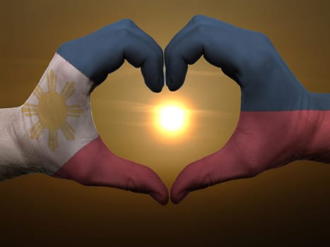 Gesture made by phillipines flag colored hands showing symbol of heart and love during sunrise