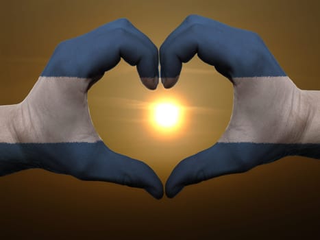 Gesture made by nicaragua flag colored hands showing symbol of heart and love during sunrise