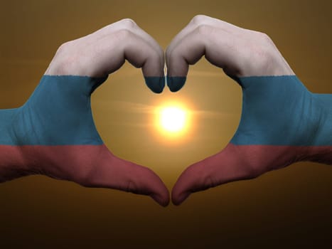 Gesture made by russia flag colored hands showing symbol of heart and love during sunrise