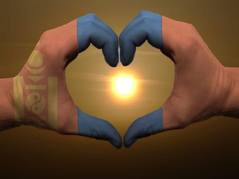 Gesture made by mongolia flag colored hands showing symbol of heart and love during sunrise