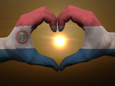 Gesture made by paraguay flag colored hands showing symbol of heart and love during sunrise