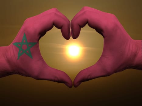 Gesture made by morocco flag colored hands showing symbol of heart and love during sunrise