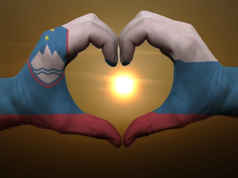 Gesture made by slovenia flag colored hands showing symbol of heart and love during sunrise