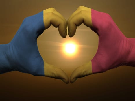 Gesture made by romania flag colored hands showing symbol of heart and love during sunrise