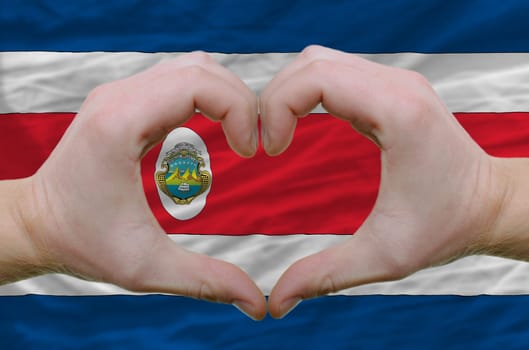 Gesture made by hands showing symbol of heart and love over costarica flag