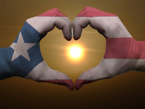 Gesture made by puertorico flag colored hands showing symbol of heart and love during sunrise