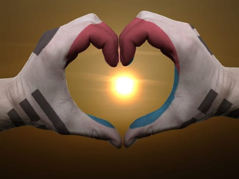 Gesture made by south korea flag colored hands showing symbol of heart and love during sunrise