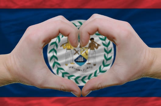 Gesture made by hands showing symbol of heart and love over belize flag