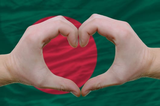 Gesture made by hands showing symbol of heart and love over bangladesh flag