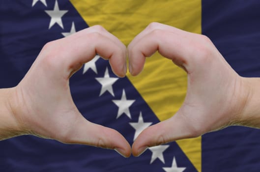 Gesture made by hands showing symbol of heart and love over bosnia herzegovina flag
