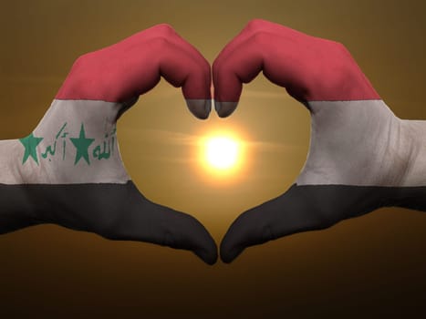 Gesture made by iraq flag colored hands showing symbol of heart and love during sunrise
