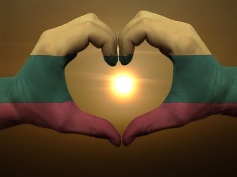 Gesture made by lithuania flag colored hands showing symbol of heart and love during sunrise