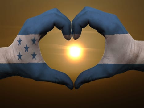Gesture made by honduras flag colored hands showing symbol of heart and love during sunrise