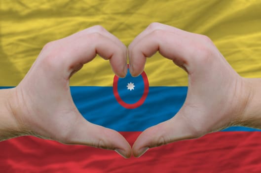Gesture made by hands showing symbol of heart and love over columbia flag