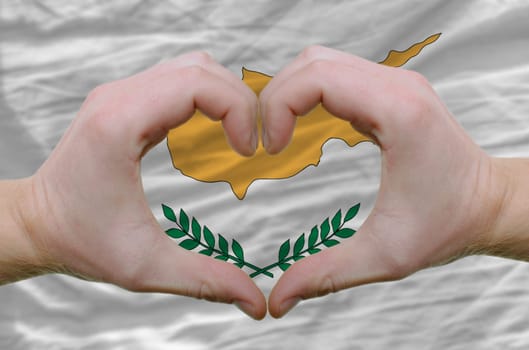 Gesture made by hands showing symbol of heart and love over cyprus flag