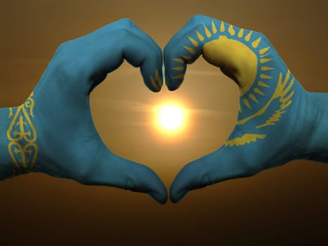Gesture made by kazakstan flag colored hands showing symbol of heart and love during sunrise