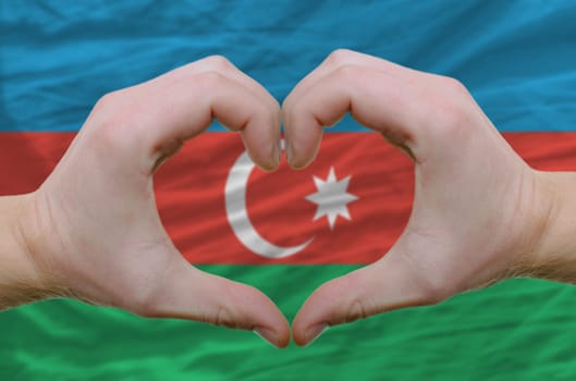 Gesture made by hands showing symbol of heart and love over azerbaijan flag