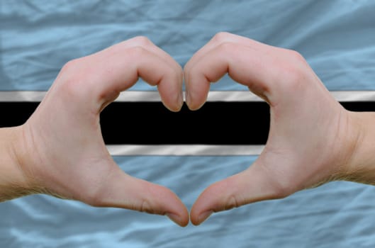 Gesture made by hands showing symbol of heart and love over botswana flag