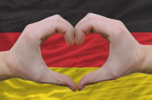 Gesture made by hands showing symbol of heart and love over germany flag
