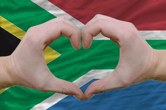 Gesture made by hands showing symbol of heart and love over soth african flag