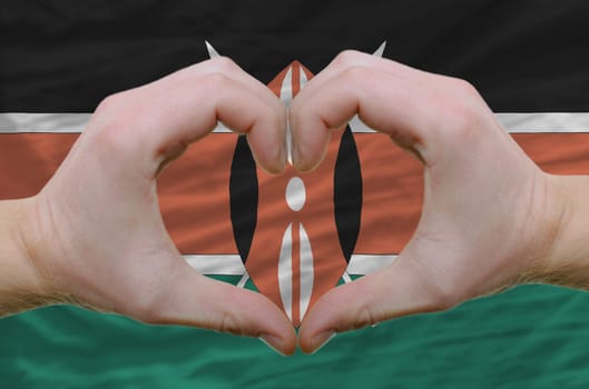 Gesture made by hands showing symbol of heart and love over kenya flag