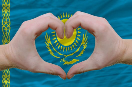 Gesture made by hands showing symbol of heart and love over kazakstan flag