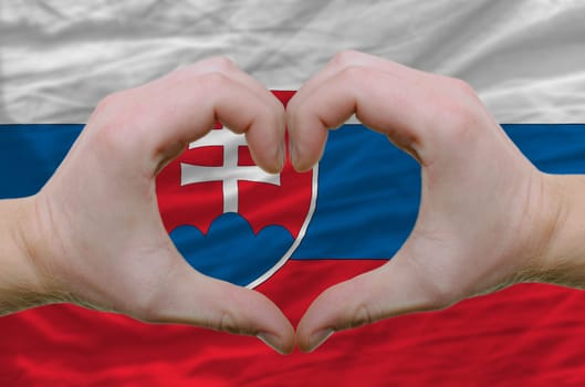 Gesture made by hands showing symbol of heart and love over slovakia flag