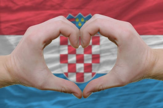 Gesture made by hands showing symbol of heart and love over Croatian flag