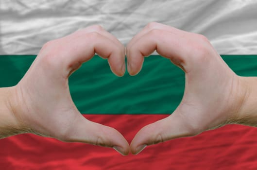 Gesture made by hands showing symbol of heart and love over bulgarial flag