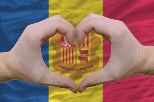 Gesture made by hands showing symbol of heart and love over Andoran flag