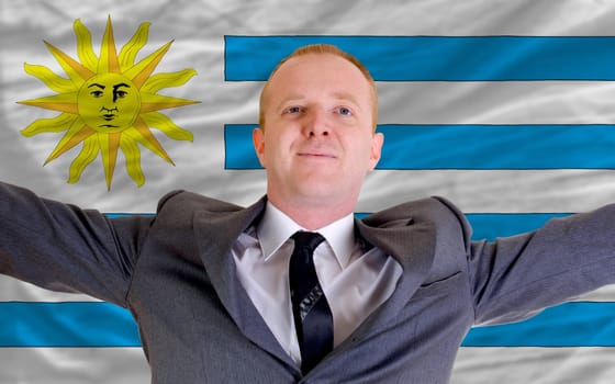 joyful investor spreading arms after good business investment in uruguay, in front of flag