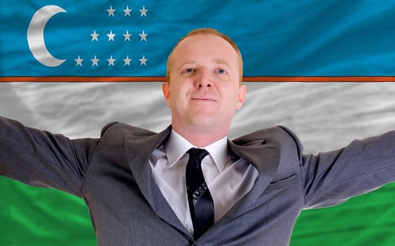 joyful investor spreading arms after good business investment in uzbekistan, in front of flag
